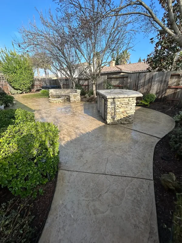 Curved stamped-concrete patio and walkway after washing, with the surface still wet