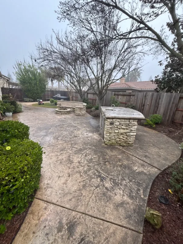 Dark buildup on a curved stamped-concrete patio and walkway before pressure washing
