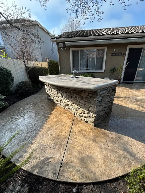 Stamped-concrete patio around the stone outdoor bar after pressure washing, while still wet