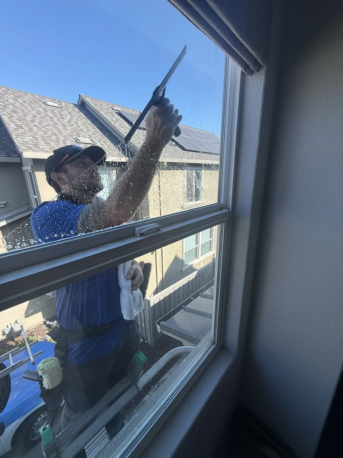 Technician using a squeegee on the exterior of a residential window